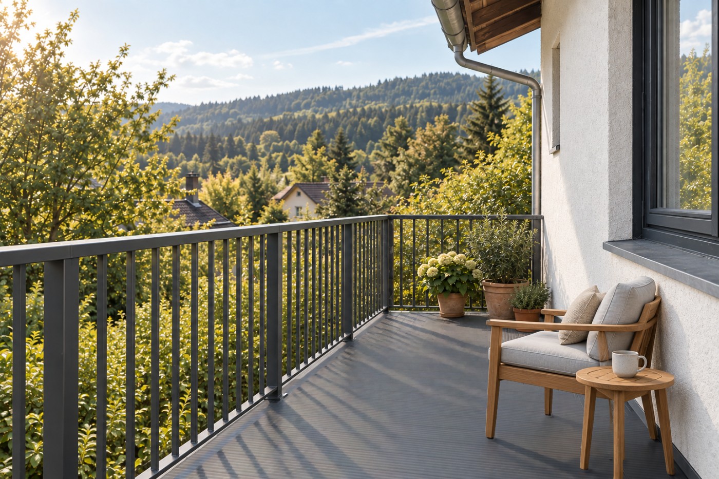 Derselbe Balkon nach der Sanierung: dunkelgraue AluTeck-Aluminiumdielen, anthrazitfarbenes Stabgeländer, Teaksessel und Beistelltisch