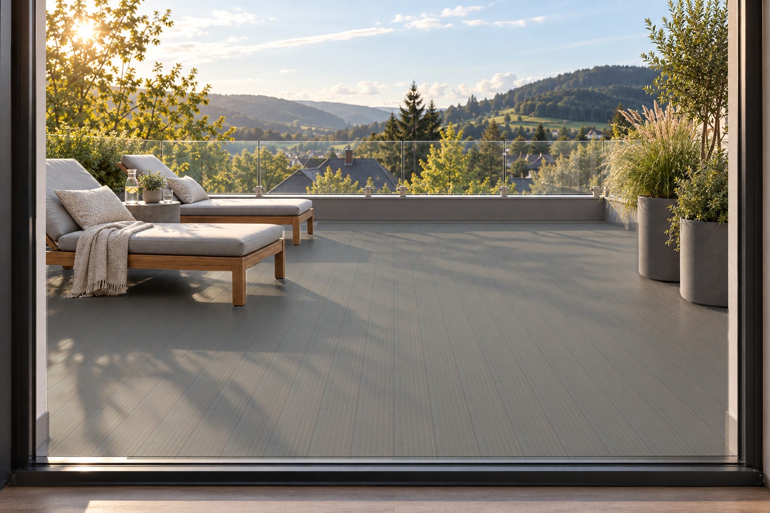 Fertige Dachterrasse mit AluTeck-Dielen Mittelgrau, zwei Liegen und Pflanzkübeln vor der Glasbrüstung